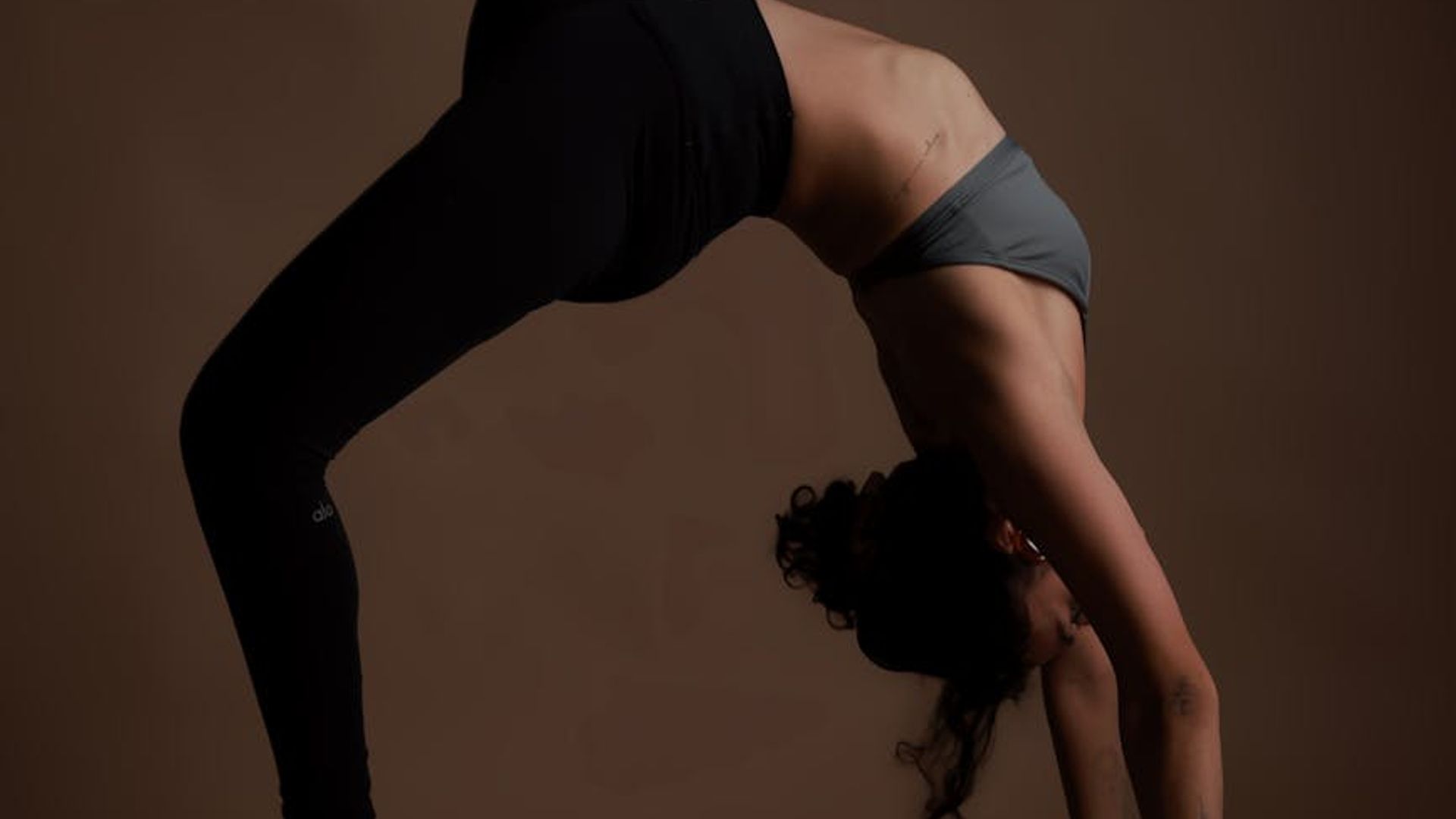 Person practicing yoga in a dark minimalist studio setting.