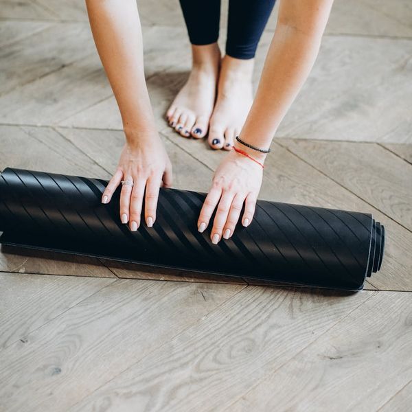 Rollup yoga mat on a dark wooden floor.